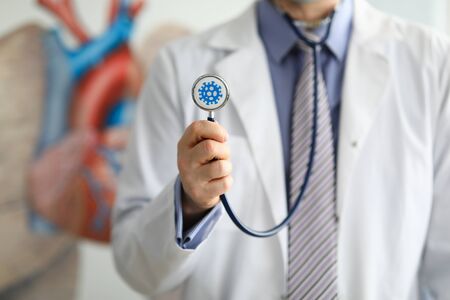 Male doctor hold in hand stethoscope with coronavirus symbol closeup. Coronavirus treatment antivirus concept.の写真素材