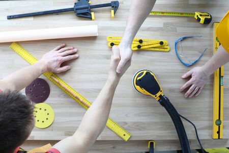 Top view of worker welcome each other and shake hands. Sander machine level replacement discs and...