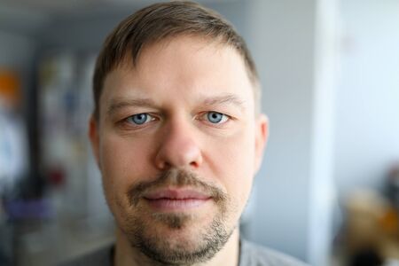Close-up of serious man taking selfie on smartphone. Macro shot of middle-aged male face....