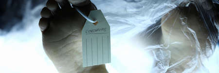 Male leg with tag lies on table in morgue. corona virus fear concept