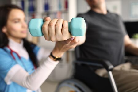 Girl doctor helps patient train with dumbbell.の写真素材