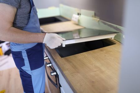 Close-up of professional handyman setting cookstove. Male in protective white gloves on kitchen. Moving day in new apartment. Renovation and repairman conceptの写真素材