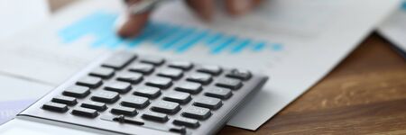 Close-up of calculator on wooden table. Accountant making annual financial statement. Worker...