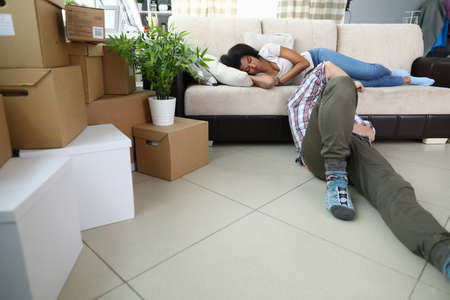 Portrait of man and woman resting after relocation. Male sitting on floor and relaxing after...