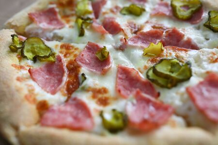 Close-up of homemade delicious round shaped pizza. Hot yummy salami double cheese parmesan tomatoes and pickle. Traditional italian food. Tasty fastfood and quick lunch conceptの写真素材