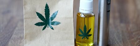 Paper organic bag with marijuana vaporizer cbd oil stand on a wooden table closeupの写真素材