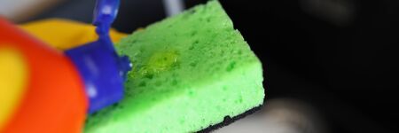 Gloved hands pour detergent for dishes on sponge. An affordable way to clean dishes. Manual way washing dishes. Safe detergent. Mechanical cleaning dishes from food debris houseworkの写真素材