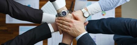 Group men in suits hold out their hands in unity. Togetherness team at meeting in office. Teamed up...