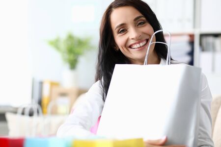 Cute girl in office presses package and laughs. Shopping plan agreed. Escort for shopping. Business shopper will help you find right styles and shades. Analysis seasonal wardrobe by good stylistの写真素材