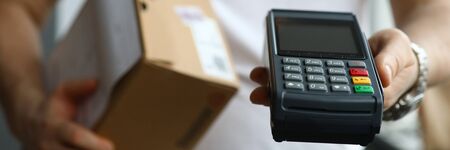 Male deliveryman hold POS terminal in hand closeup background. Fast delivery post package courier...