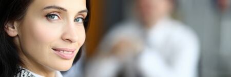 Smiling woman turned around in front her man. Feminine woman leader performs work carefully. Diplomatic style leadership and communication with employees. Teamwork and collaborationの写真素材