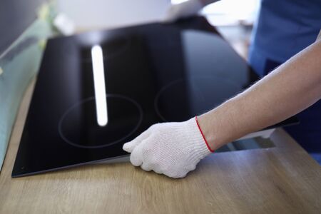 Close-up of professional worker setting cookstove in kitchen room. New modern cooker. Man wearing protective white gloves for work. Renovation and furniture change conceptの写真素材
