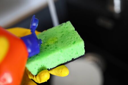 Gloved hands pour detergent for dishes on sponge. An affordable way to clean dishes. Manual way washing dishes. Safe detergent. Mechanical cleaning dishes from food debris houseworkの写真素材