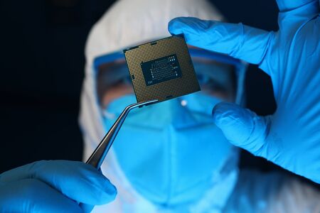 Man in uniform holds microprocessor with forceps. Software-controlled device for processing...