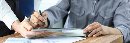 Signing electronic document on tablet with stylus. Company employee holds electronic device in his...