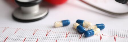 Cardiogram prescribing and doctor visits clinic. Prescription of drugs based on cardiogram and medical examination. With stethoscope and capsule with medicine lie on form with cardiogram.の写真素材