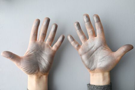 Close-up of persons dirty hands in silver paint. Man after painting room walls. Interior decoration....
