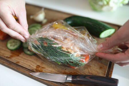 Close-up of woman cooking delicious meal for family. Female prepare vegetables for baking in oven. Yummy and healthy dish. Cooking on wooden cutting board. Cuisine conceptの写真素材