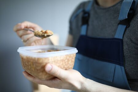 Close-up of service man worker holding plastic container with beans lunch. Break from work for...