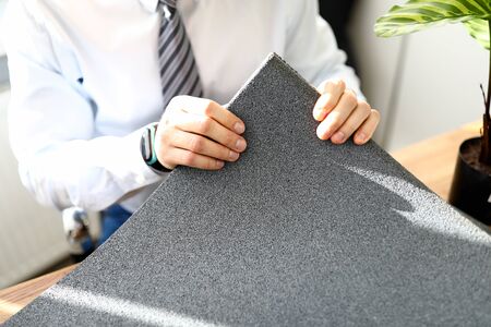 Close-up of business male holding grey material for apartment renovation. Interior designer office. Construction house. Successful agency and talented architect conceptの写真素材