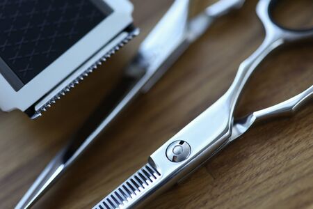 On table are hairdressing scissors and trimmer. Buy scissors for beginner hairdresser. Hot scissors haircut service. Fashionable mens haircut. Modern professional equipment for hairdressersの写真素材