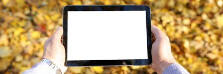 Close-up of persons hands holding modern tablet with white screen. Man with trendy device standing...