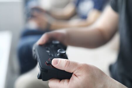 Two male friends play video games against home background. Gaming console concept