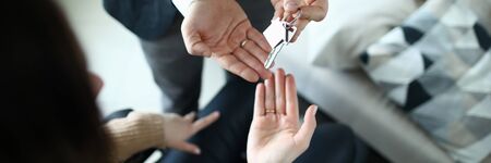 Male businessman hand passes the key to a woman from new housing. Disabled person help conceptの写真素材