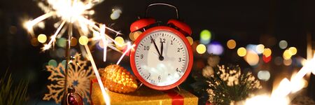 Red alarm clock with christmas gifts against night city background. Happy New Year conceptの写真素材