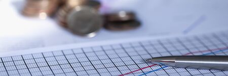 Silver pen lies on report with graph next to coin. Scaling business helps capture market and dictate...