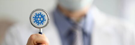 Male doctor hold in hand stethoscope with coronavirus symbol closeup. Coronavirus treatment...