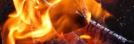 Close-up burning firewood in fire, black coals. Fire crackling in fireplace. Comfort and warmth from...