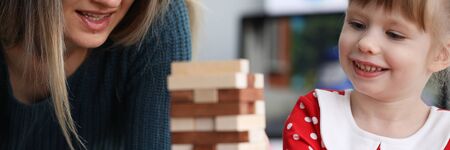 Mom and daughter are sitting at table playing game. Vision attention memory and perception child. Girl has good memory and concentration. Interesting entertainment for family circleの写真素材