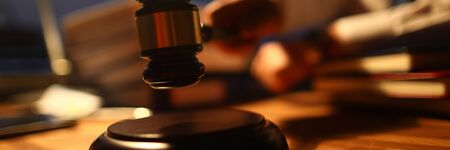 Focus on judge utility on wooden table used to maintain order and pronounce a verdict in courtroom in front of many people. Rule of law and strict court conceptの写真素材