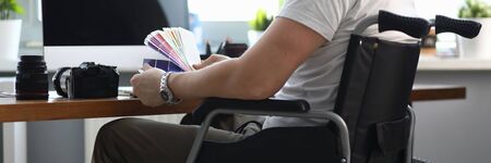 Close-up of professional designer working in office holding colourful palette. Male sitting in...