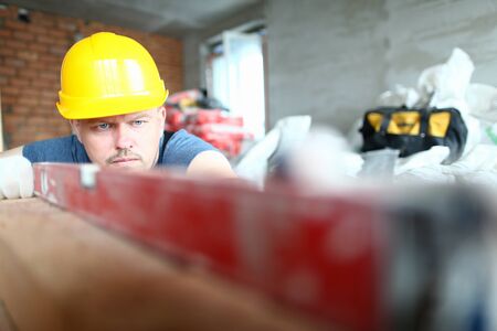 Close up of male worker in gloves and yellow helmet working in manufactured joinery workshopの写真素材