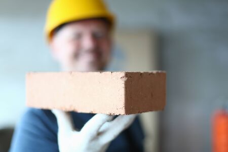 Close up of man builder arm holding building material for making walls, pavements and other elements in masonry constructionの写真素材