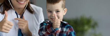 Portrait of doctor and kid showing thumbs up smiling on camera. Planned appointment at medical worker cabinet for diagnostic. Modern medicine and healthcare conceptの写真素材