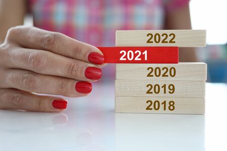 Female hand hold red wooden block with 2021 sign closeup. Chops and changes conceptの写真素材