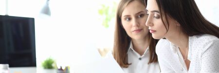 Portrait of smart businesswoman standing near concerned colleague and looking at important document with significant information about corporation profit. Accounting office conceptの写真素材