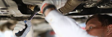 Close-up view of mechanic fixing car with wrench. Male below transport facility repair damage....