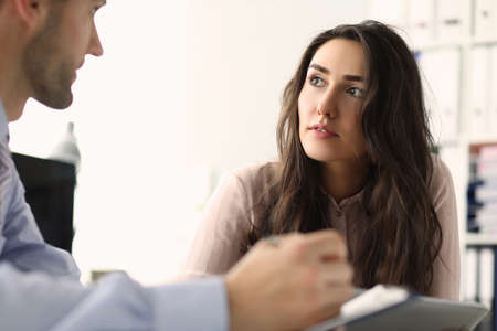 Two young employees looking at each other in the office while talking. Teamwork and partnership...