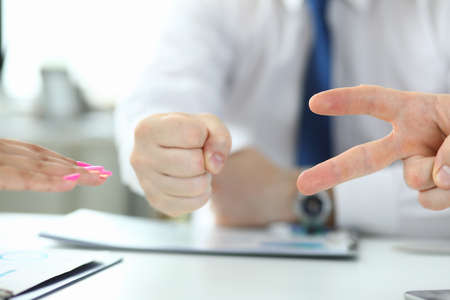 Close up of table with group of people playing rock paper scissors game in the office. Rock, paper, scissorsの写真素材