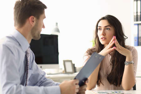 Two young employees discussing their work while sitting in the office. Teamwork and partnership...