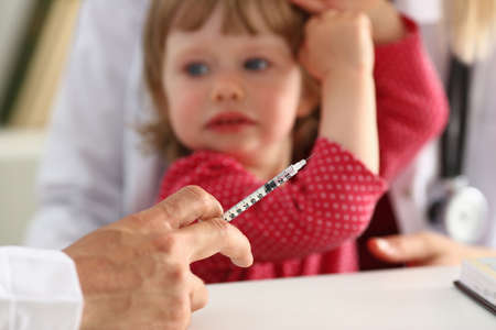 Cropped photo of male pediatrician making vaccination to small girl, while doctor holding a syringe. Medicine and care conceptの写真素材