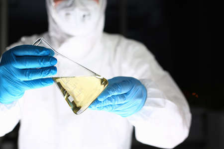 Cropped photo of male hands wearing protective blue gloves and holding flask in the laboratoryの写真素材