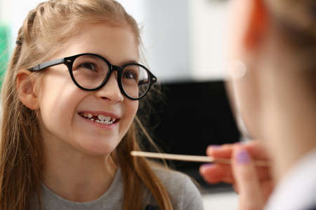 Close up of smiling cute little girl looking at the doctor before checking throat in the clinicの写真素材