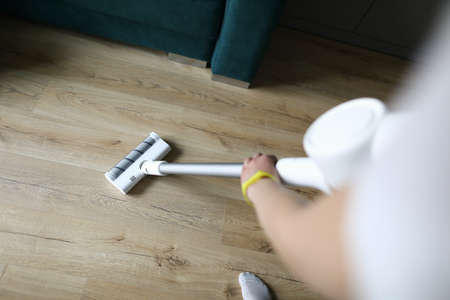 Female hand vacuums floor covering in an apartment. Purchase powerful model with smooth power...