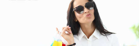 Luxurious woman in sun glasses carries shopping. Woman knows about all necessary retail outlets and has significant discount cards in them. Acquisition most trendy fashionable things seasonの写真素材