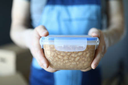 Male loader shows plastic box with homemade food. Worker in uniform shows food in container. Vegan...